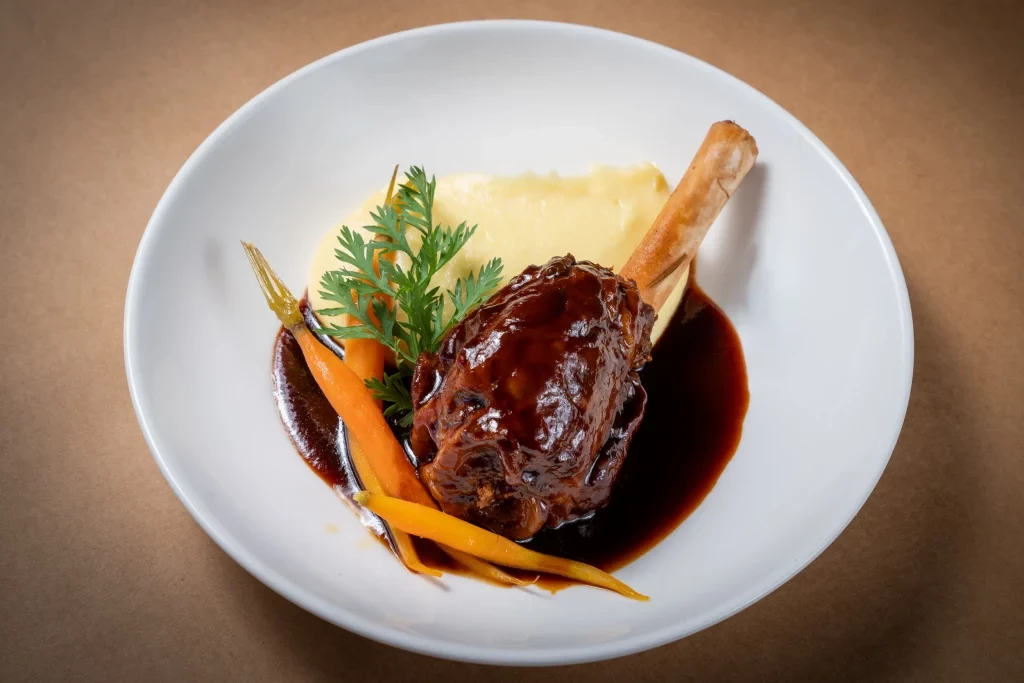 Stunningly served Lamb Shank with the carrot and mint leaves.