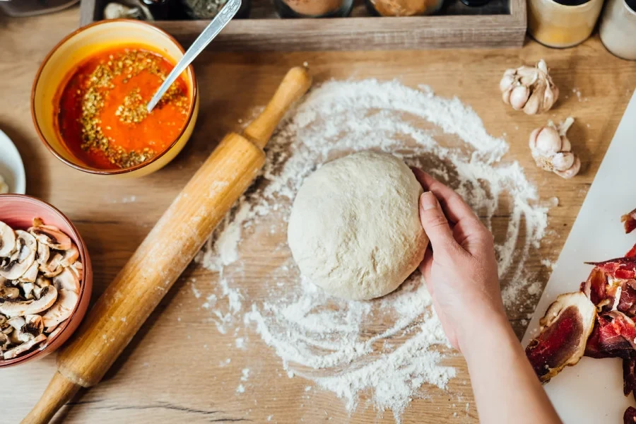 A pizza dough resting on floured surface with a rolling pin.