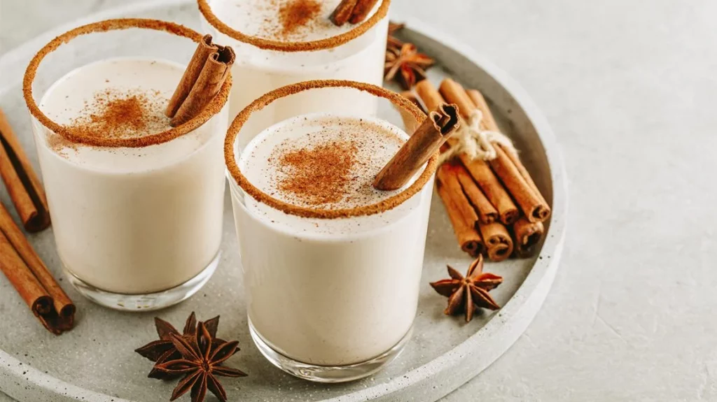 Eggnog with cinnamon stick and ground cinnamon on the glass rim