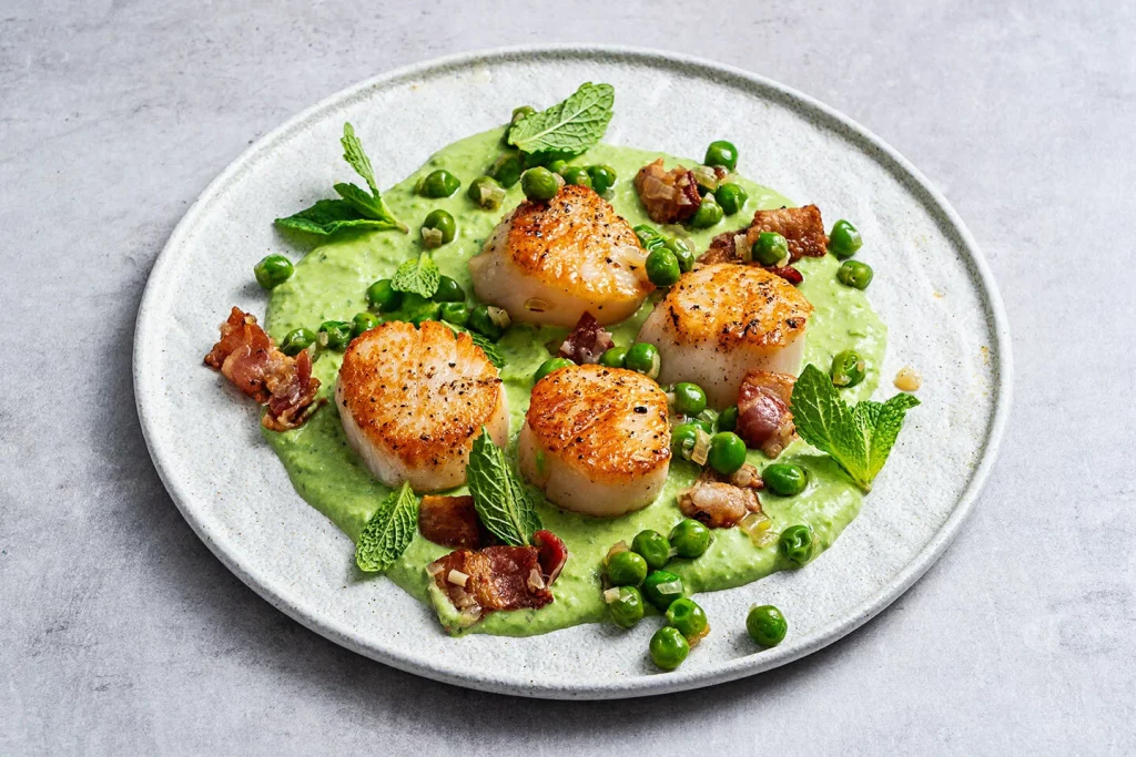 Scallops with peas, sauce and mint leaves