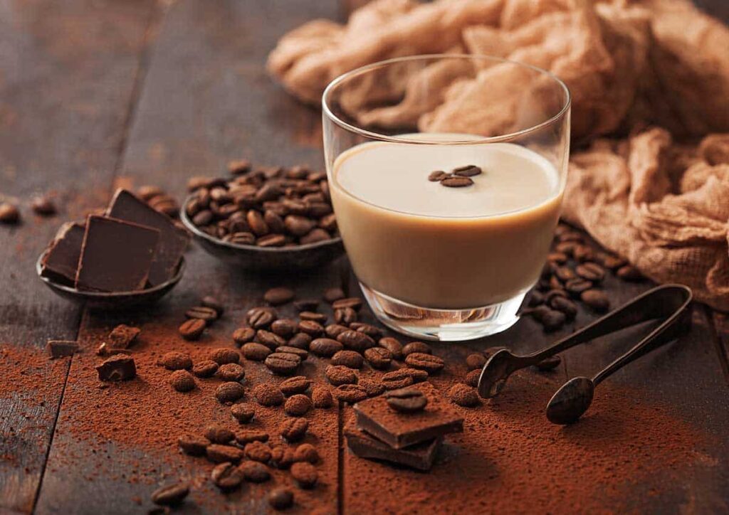 Glass of Irish cream breve with ice cubes, coffee beans and powder with dark chocolate