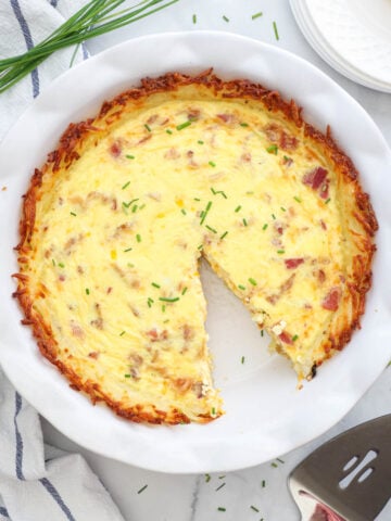 Hash Brown Quiche ona white plate missing a piece.