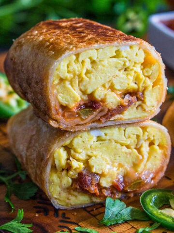 Breakfast Burritos with eggs, bacon, cheesy, and salsa cut in half and stacked.