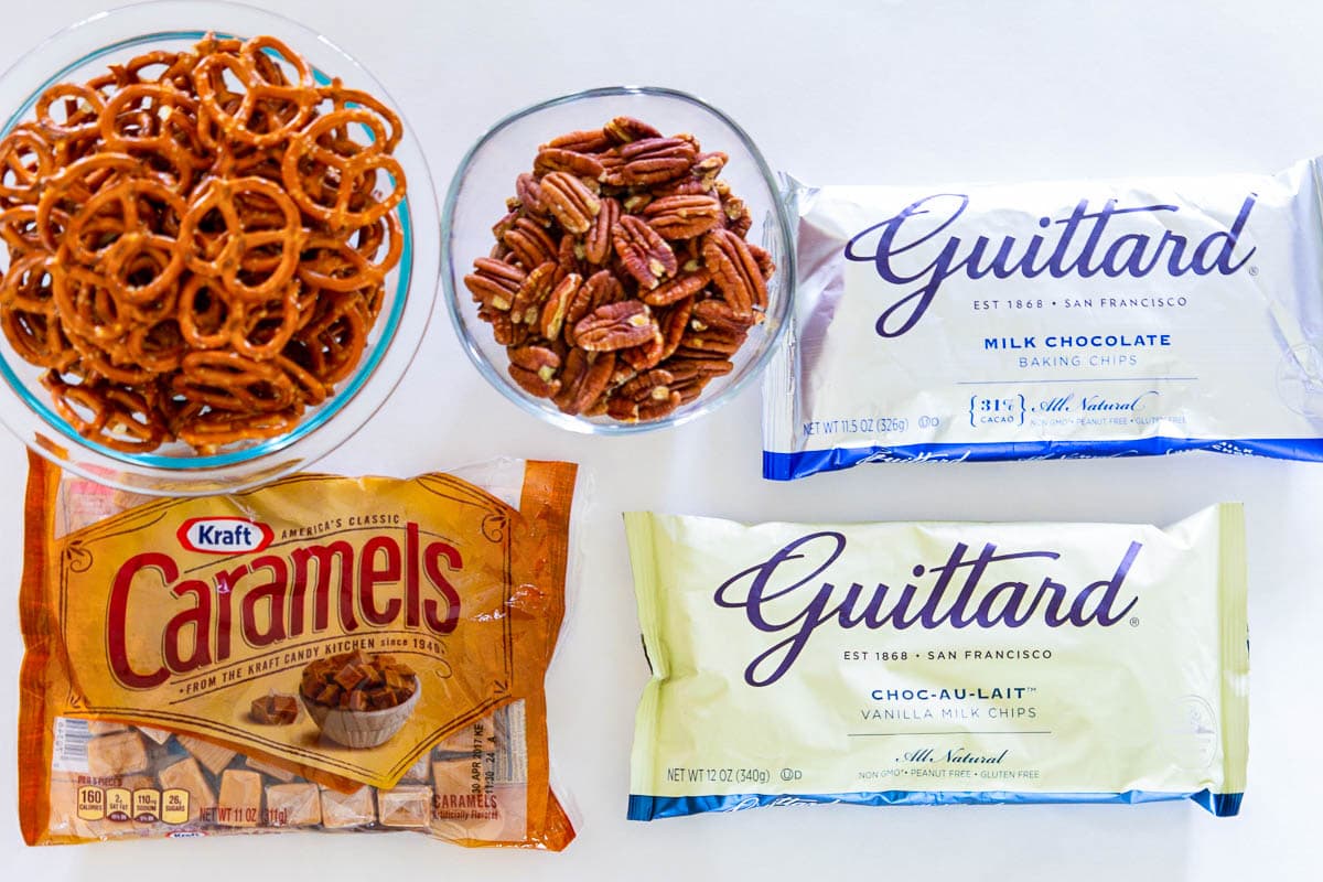 Ingredients for Chocolate Caramel Pretzel Bars: pecans, pretzels, caramels, white chocolate, and milk chocolate.