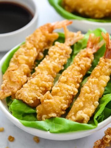 close up image of crispy fried shrimp tempura on a plate lined with butter lettuce leaves