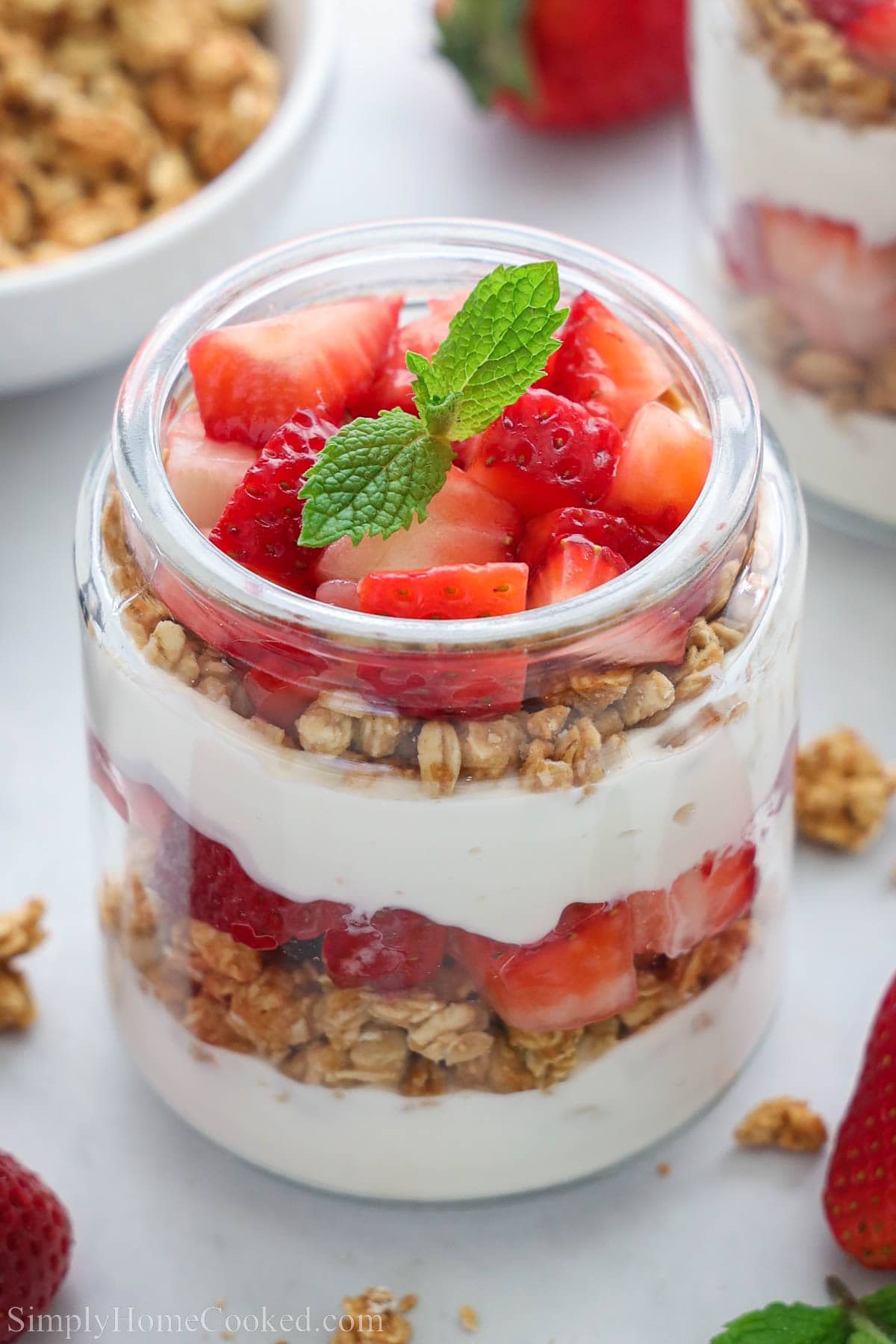 Strawberry Parfait in a jar with granola, honey, and strawberries and topped with mint.