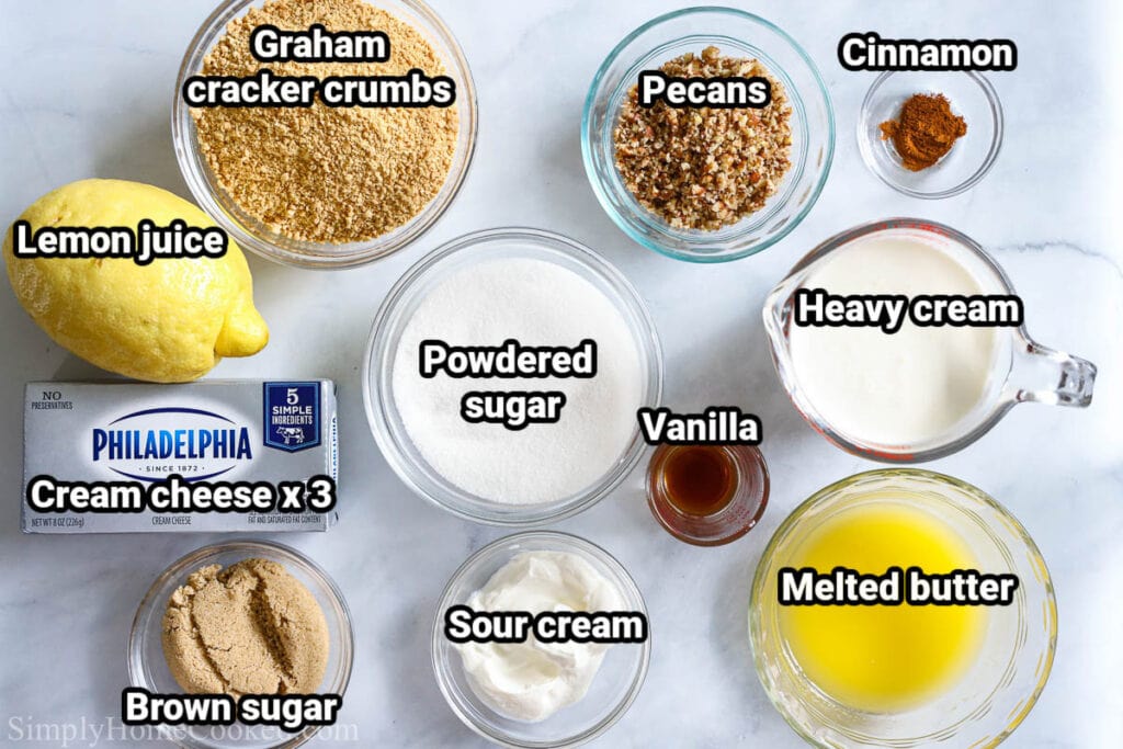 Ingredients for No-bake Cheesecake Bars: graham cracker crumbs, lemon juice, pecans, cinnamon, heavy cream, melted butter, powdered sugar, vanilla, sour cream, cream cheese, and brown sugar.