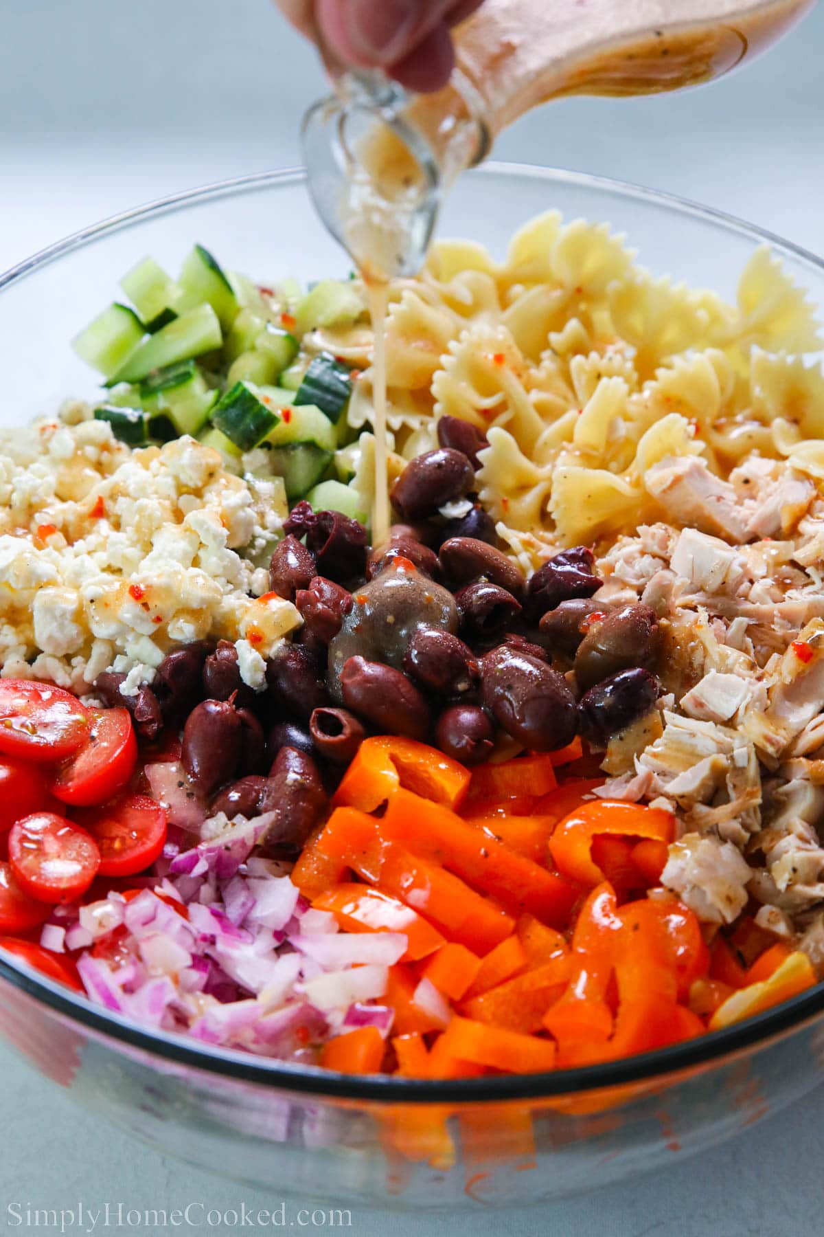 Greek Chicken Pasta Salad Greek Chicken Pasta Salad being drizzled with Greek dressing.