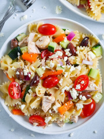 Greek Chicken Pasta Salad topped with feta cheese on a plate.