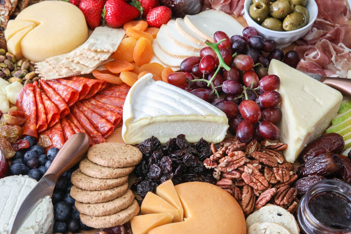 Close up image of Ultimate Charcuterie Board with meats, cheeses, nuts, fruits, spreads, olives, and crackers.
