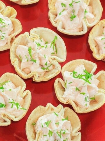 smoked salmon appetizer cream cheese tortillas cups on a red plate