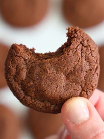 Close up image of a hand holding a bitten Nutella cookie.
