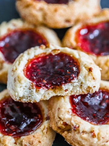Raspberry Thumbprint Cookies in a pile with one missing a bite.
