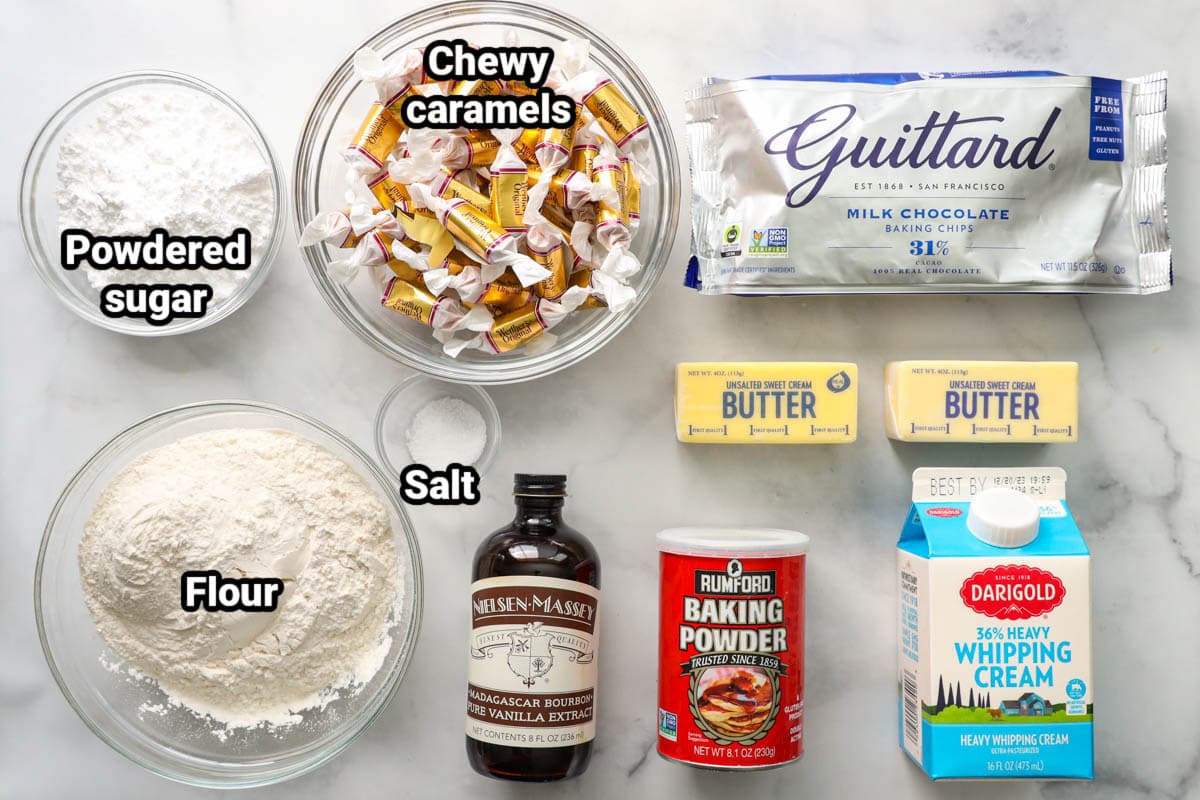 Ingredients for Twix Cookies: powdered sugar, flour, salt, chewy caramels, milk chocolate chips, butter, vanilla, heavy cram, and baking powder.