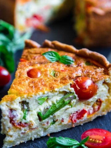 Slice of Quiche Lorraine with asparagus and cherry tomatoes.